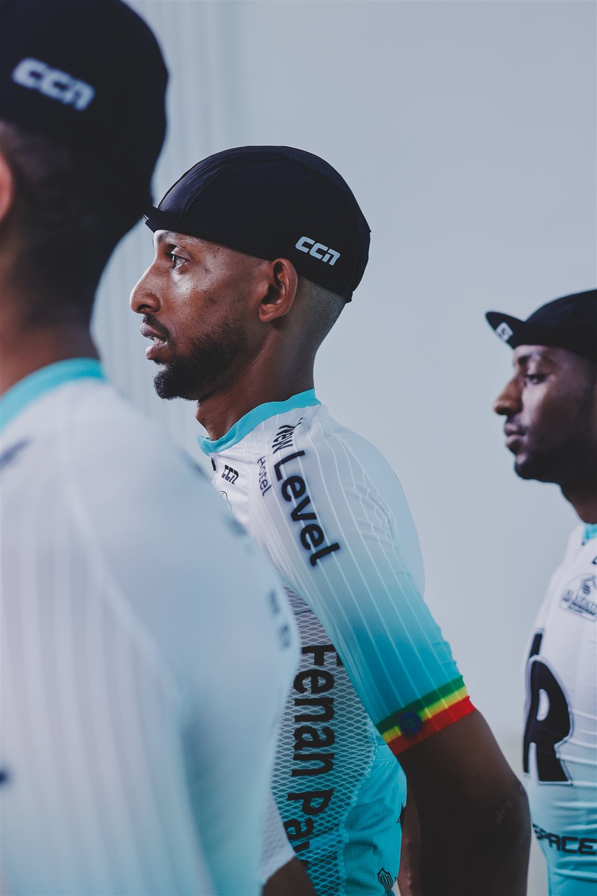 Profile of a rider in a black cap, other riders blurred beside him