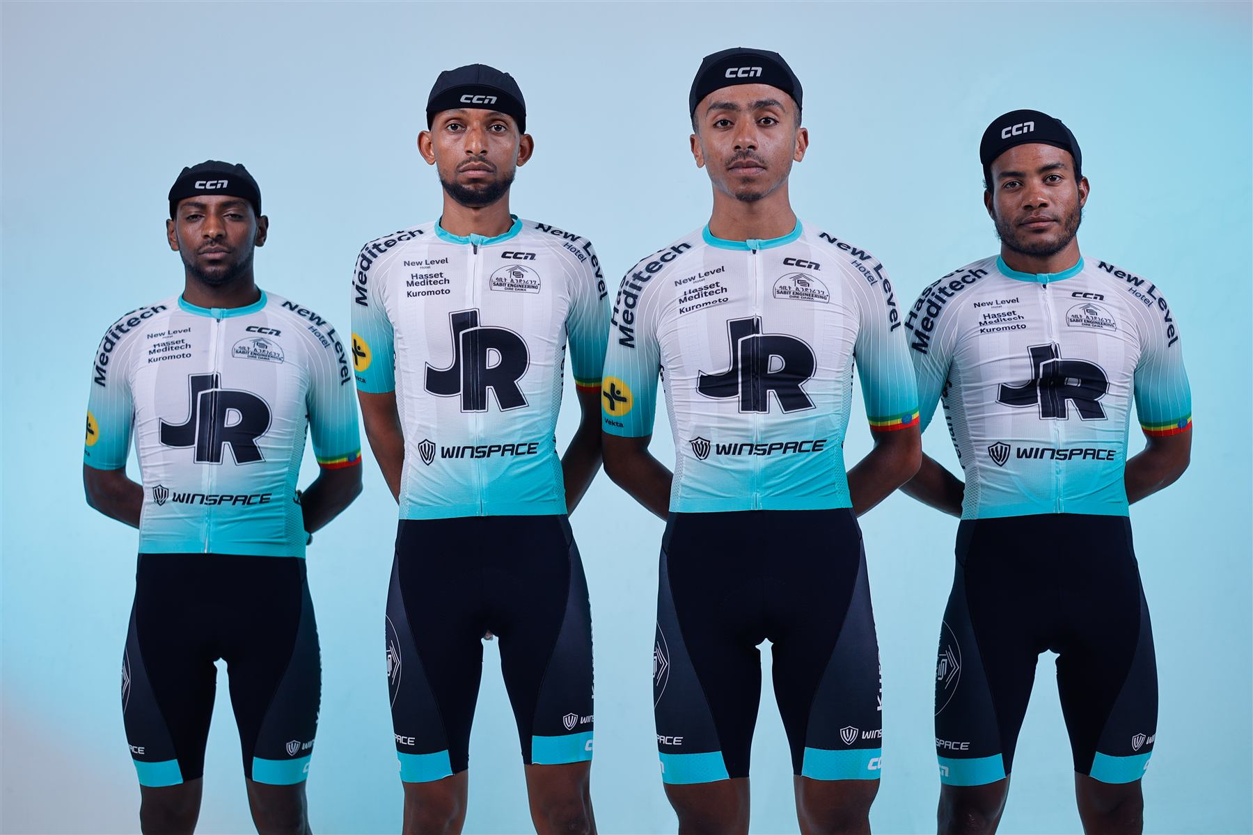 Four JR Pro Cycling riders in team kit standing in line