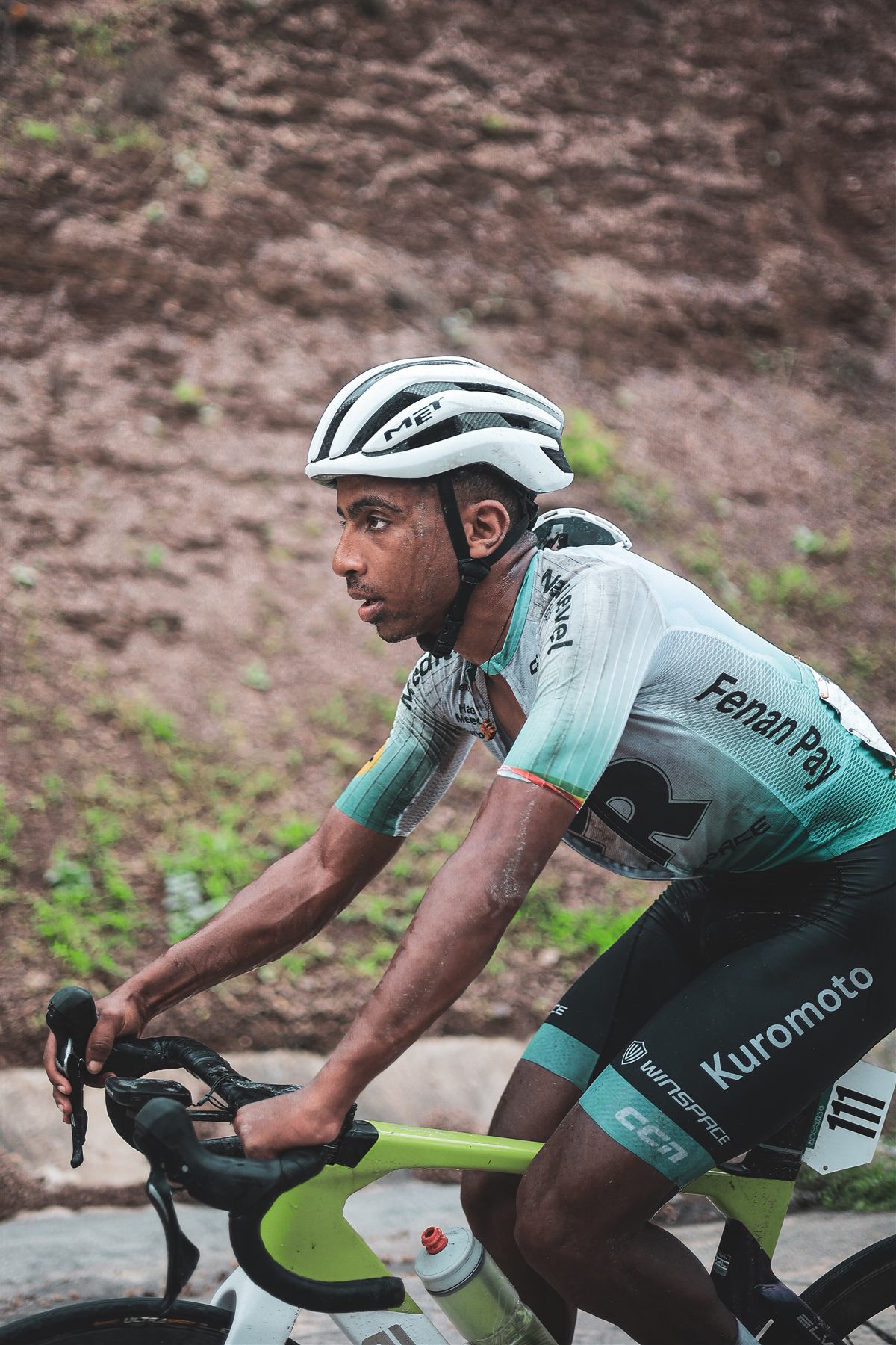 A rider climbing a wet road in JR kit
